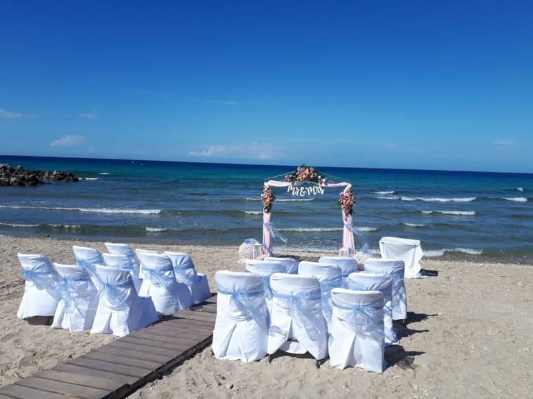 a group of people standing on a beach with chairs and tables