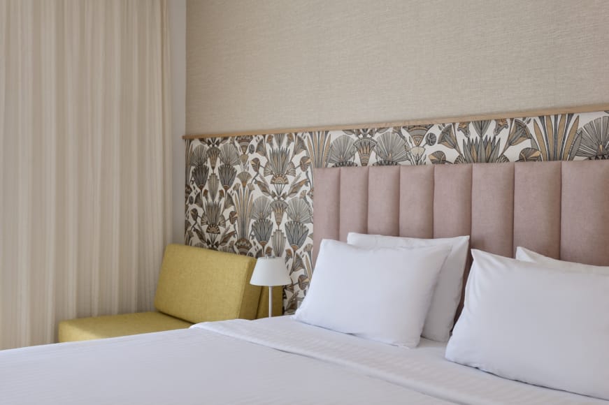 a bed with a yellow chair and a lamp