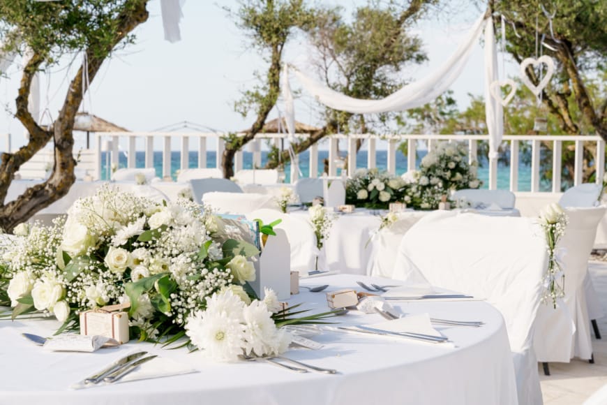 a white table with white chairs and flowers on it