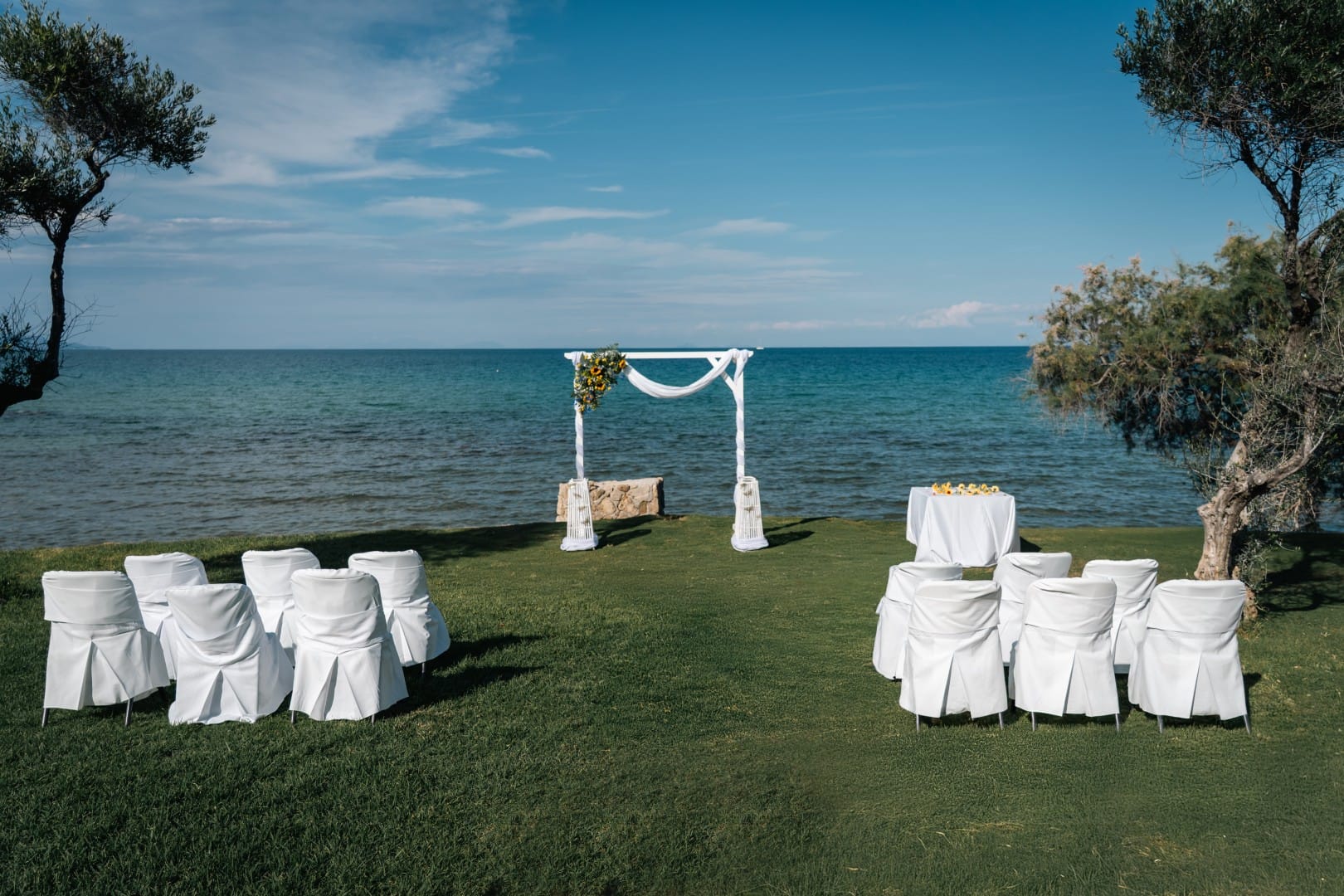 a group of white chairs on a grassy hill by the water