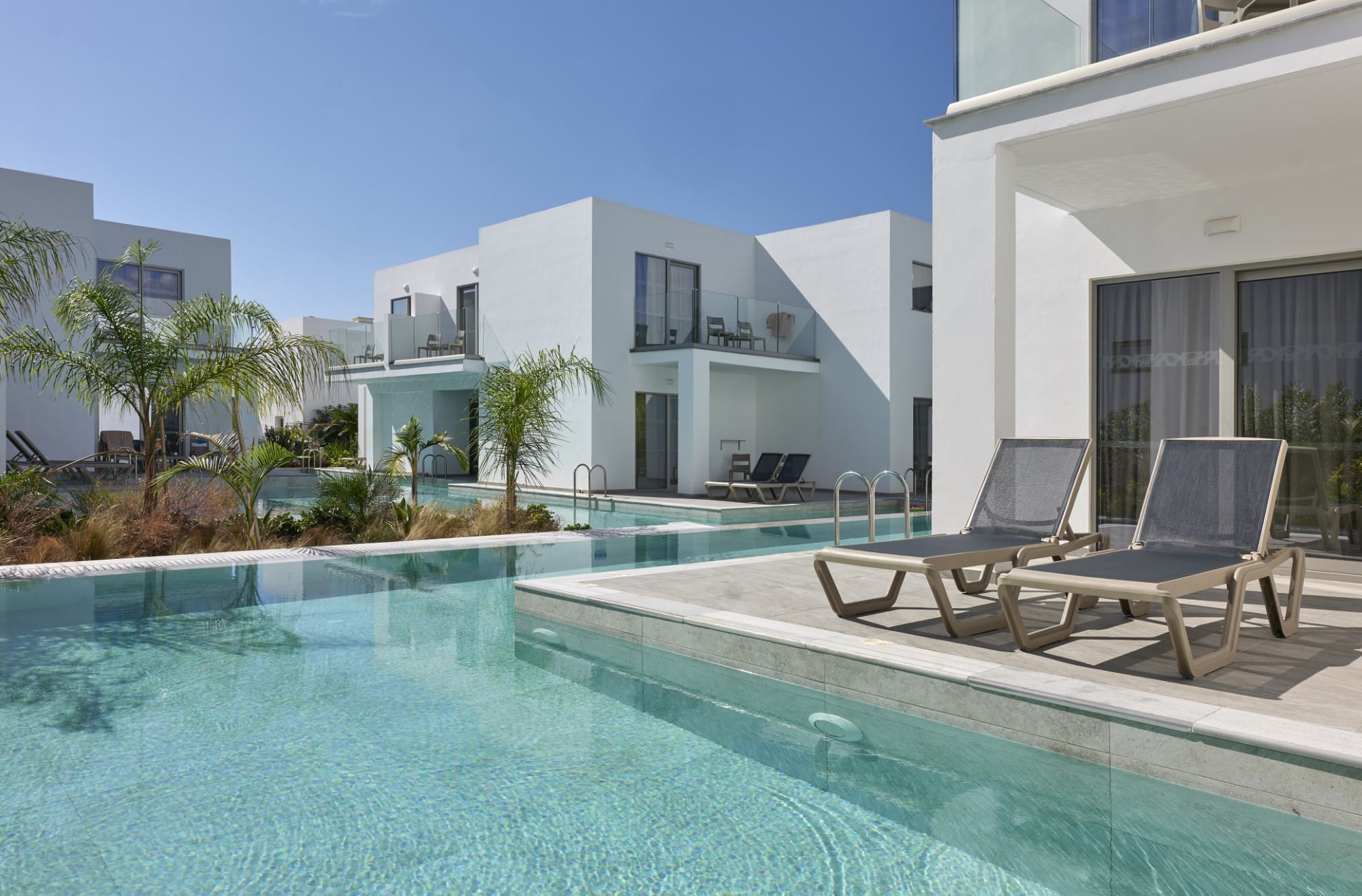 a swimming pool with chairs and a building in the background