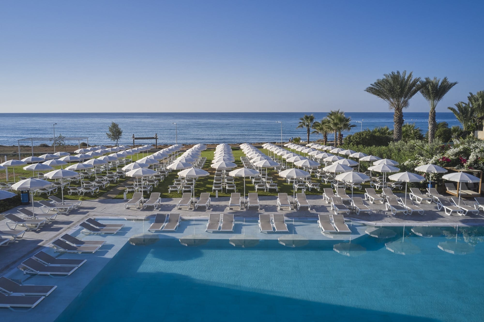 a pool with umbrellas and chairs by a beach