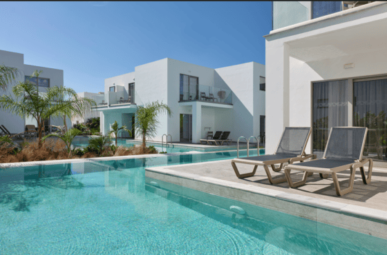a swimming pool with chairs and a building in the background