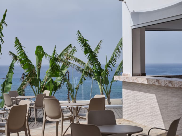 a patio with tables and chairs and palm trees