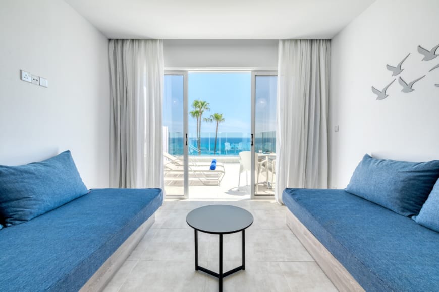 a room with blue couches and a table with a view of the ocean