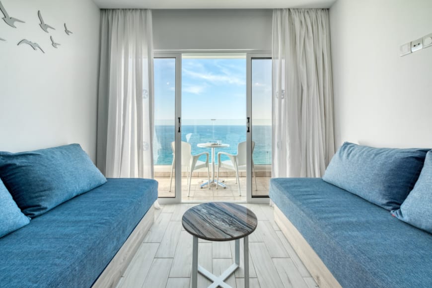 a room with blue couches and a table with a view of the ocean