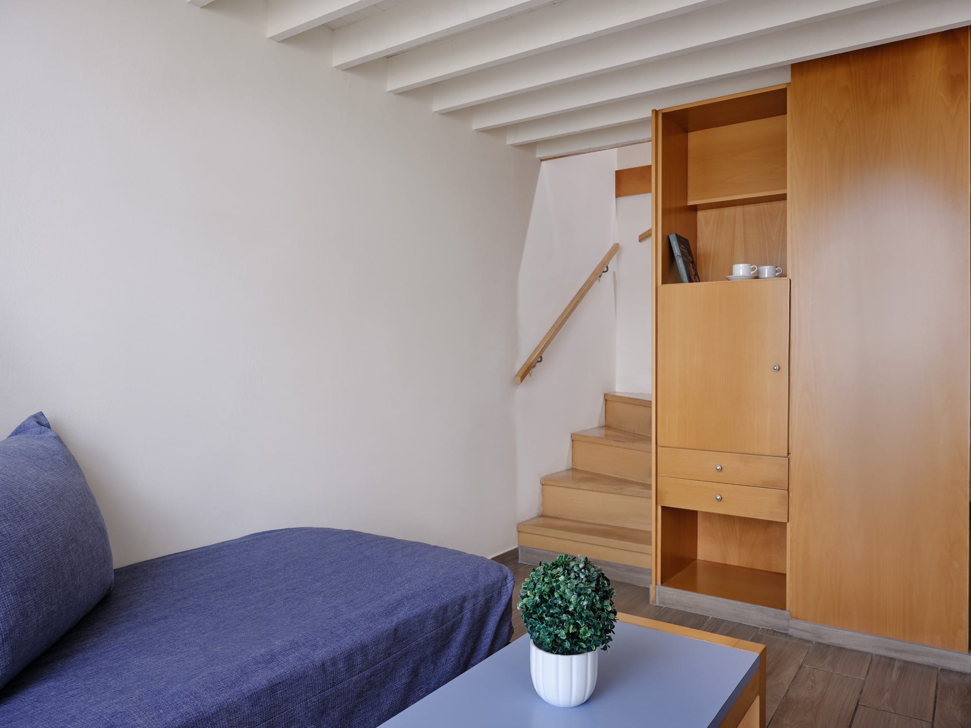 a room with a staircase and a plant in a pot