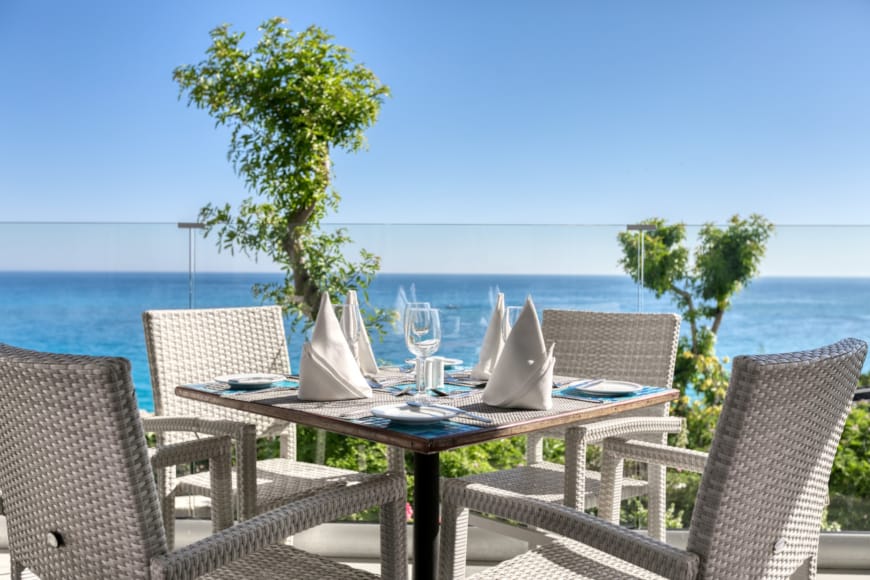 a table with chairs and a tree by the ocean