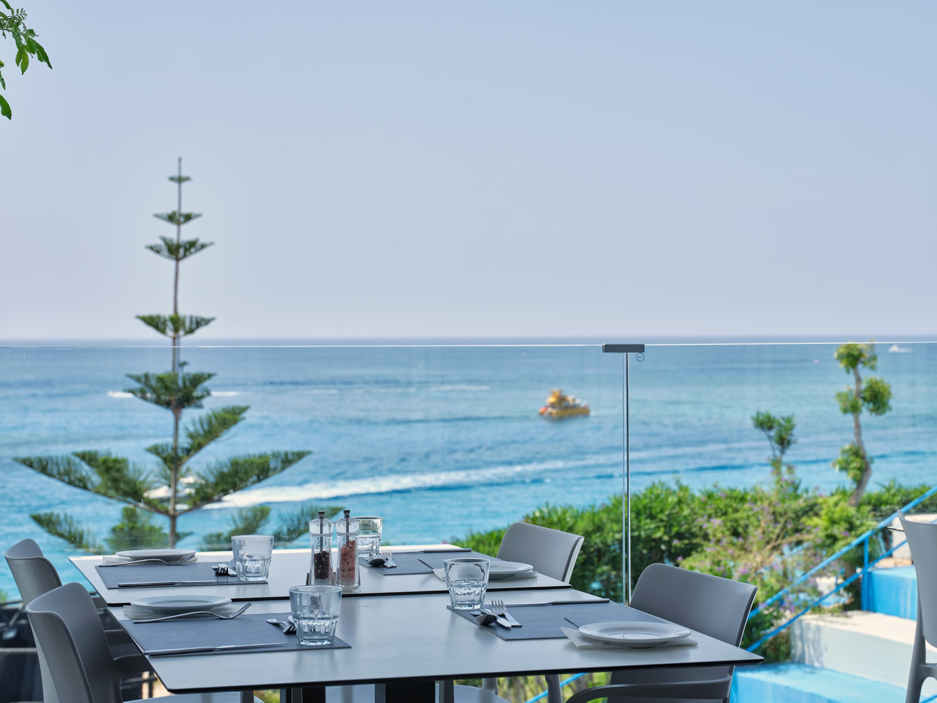 a table with chairs and glasses on it by a body of water