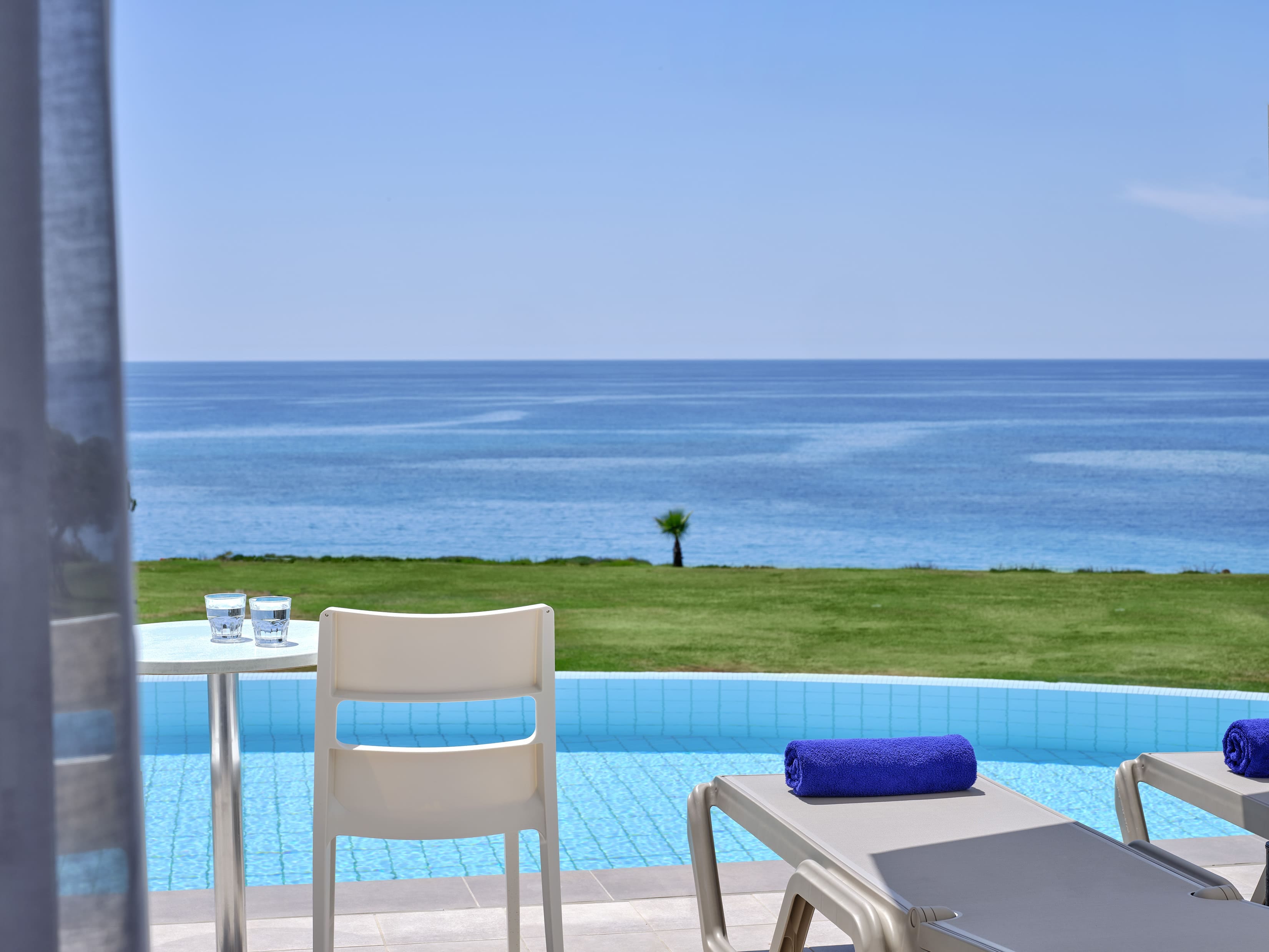 a deck with chairs and a table by a body of water