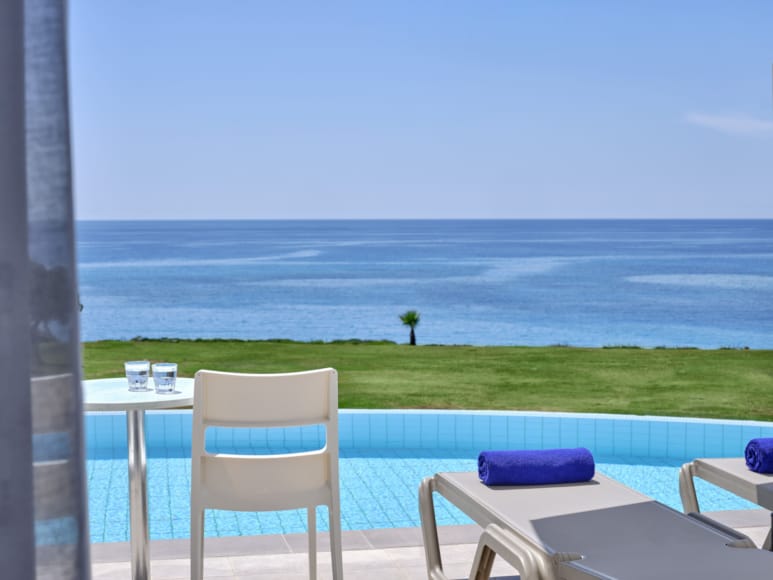 a deck with chairs and a table by a body of water