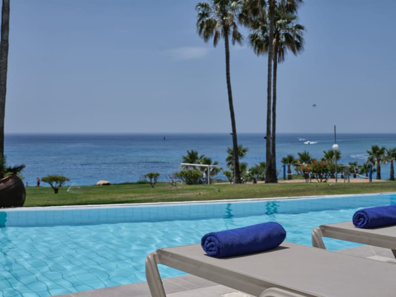 a pool with palm trees and a body of water in the background
