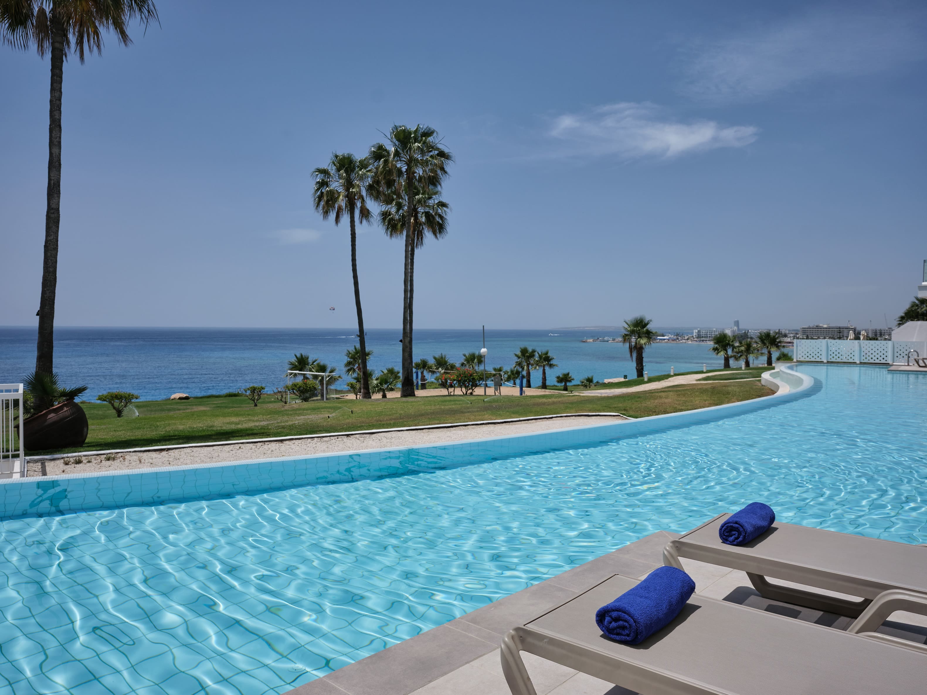 a pool with palm trees and a beach in the background