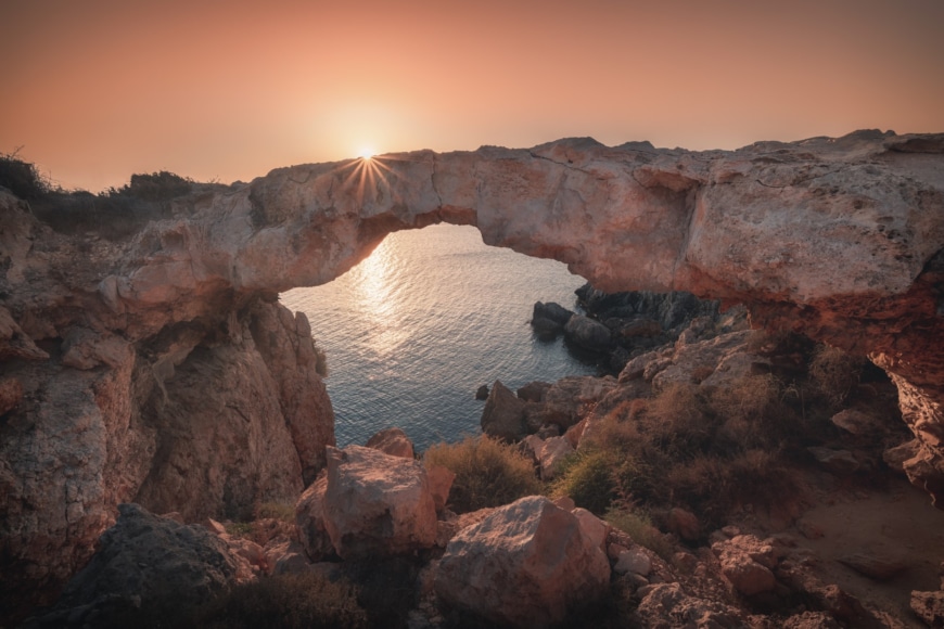 a rocky cliff with a body of water in the distance