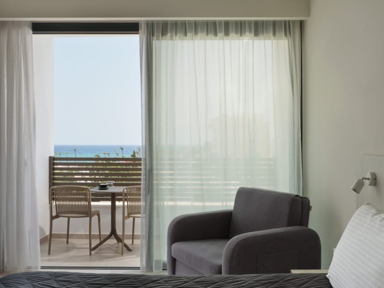 a room with a table chairs and a window with a view of the ocean