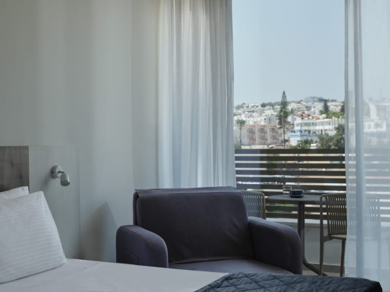 a room with a window and a chair with a table and a bed