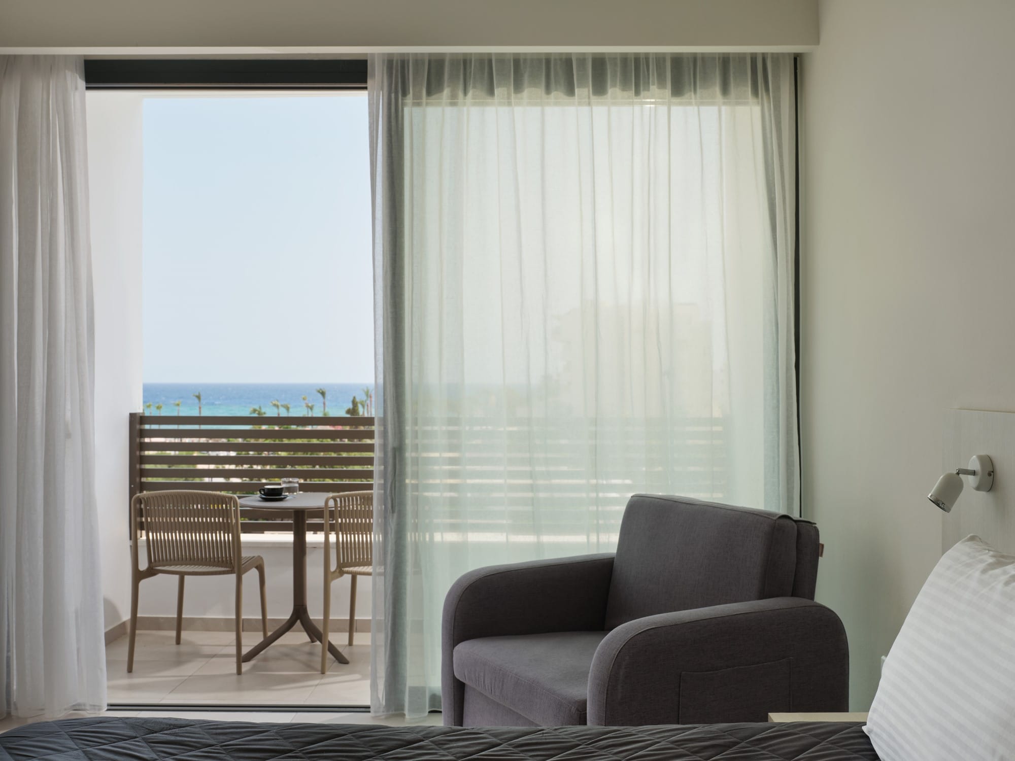 a room with a table chairs and a window with a view of the ocean