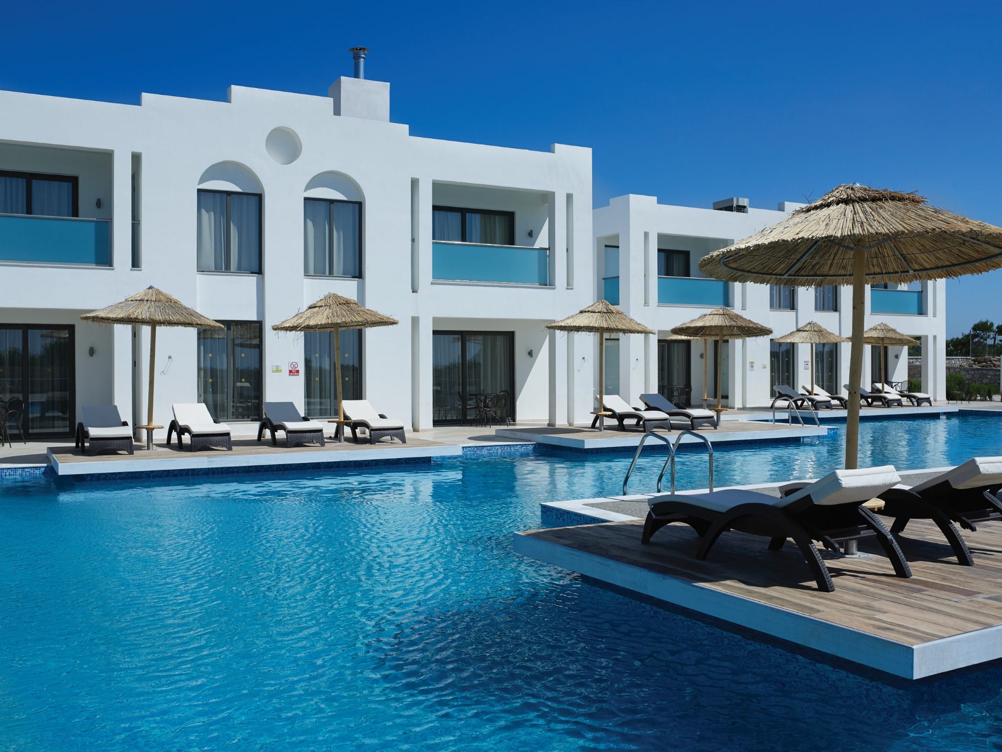a pool with lounge chairs and umbrellas by a building
