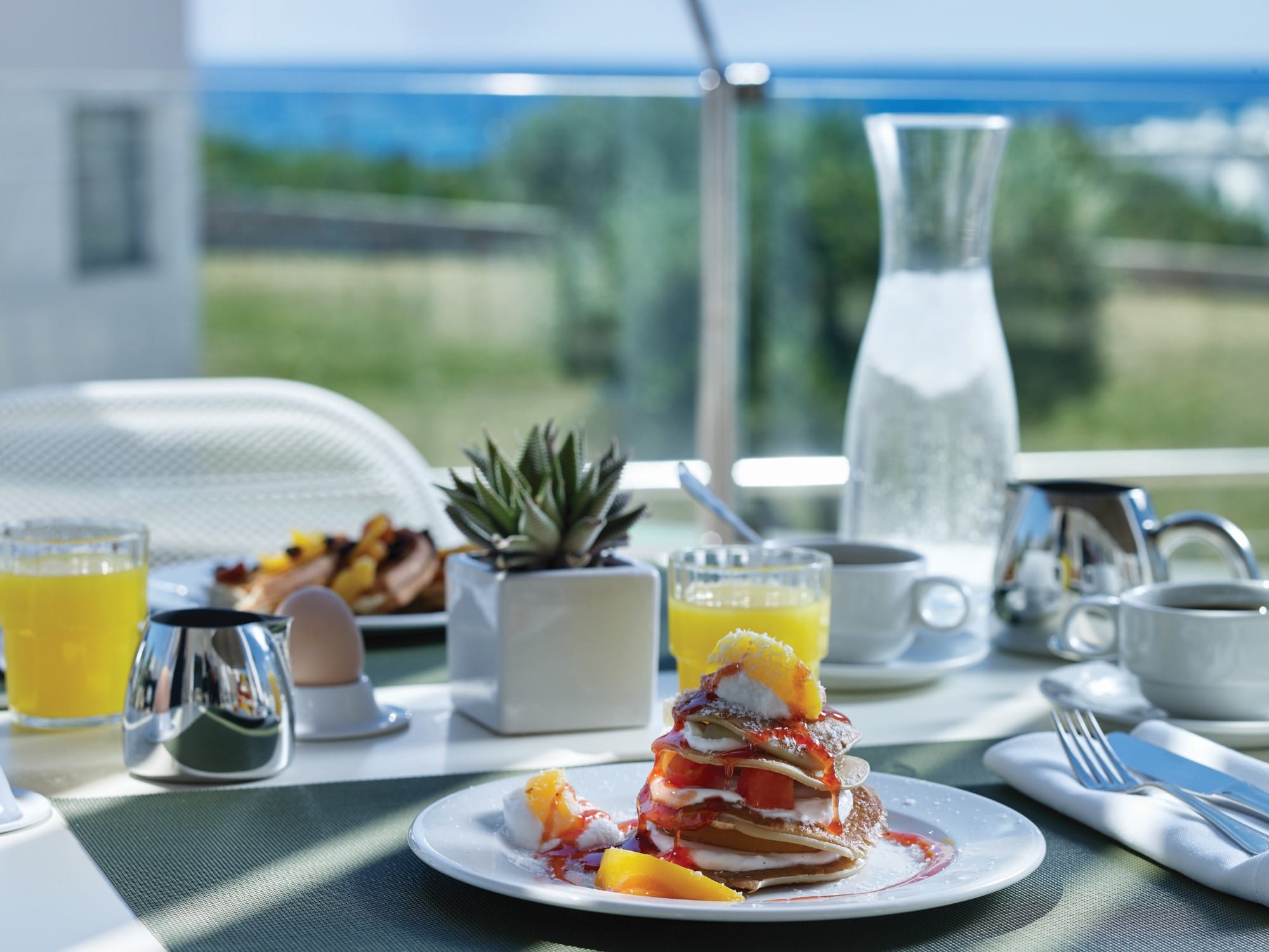 a breakfast table with a glass of juice and a plate of fruit