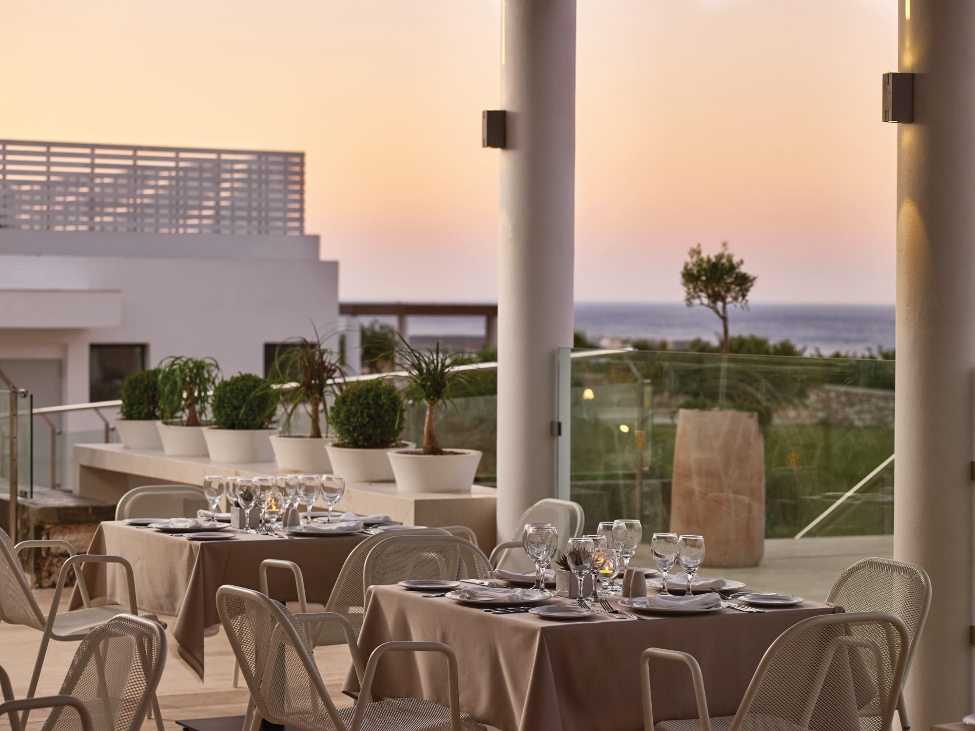 a set of tables and chairs on a balcony overlooking the ocean