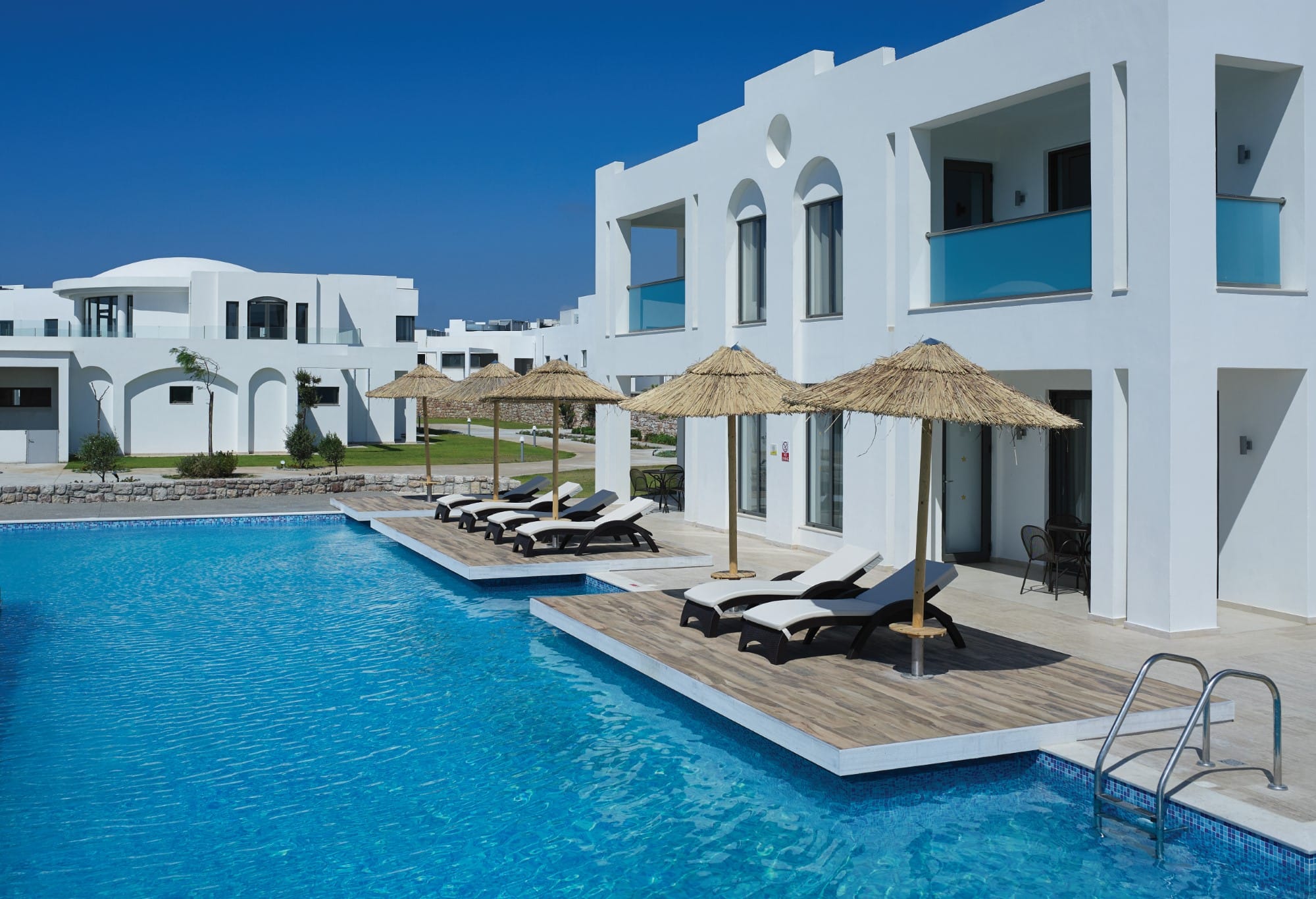 a pool with lounge chairs and umbrellas by a building