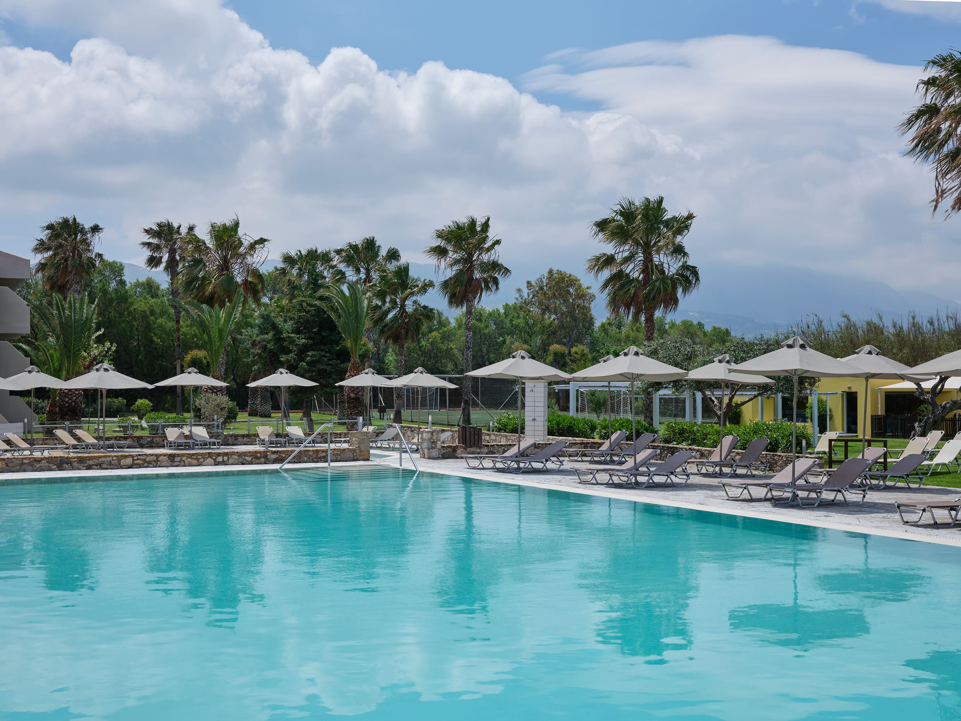 a pool with umbrellas and chairs by a beach