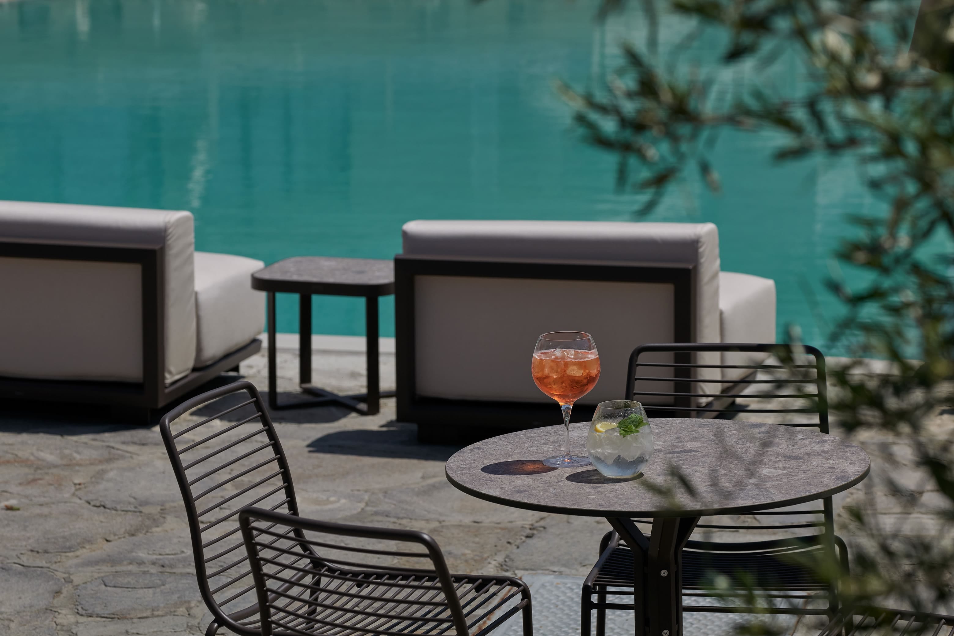 a table with a glass of wine on it and chairs around it