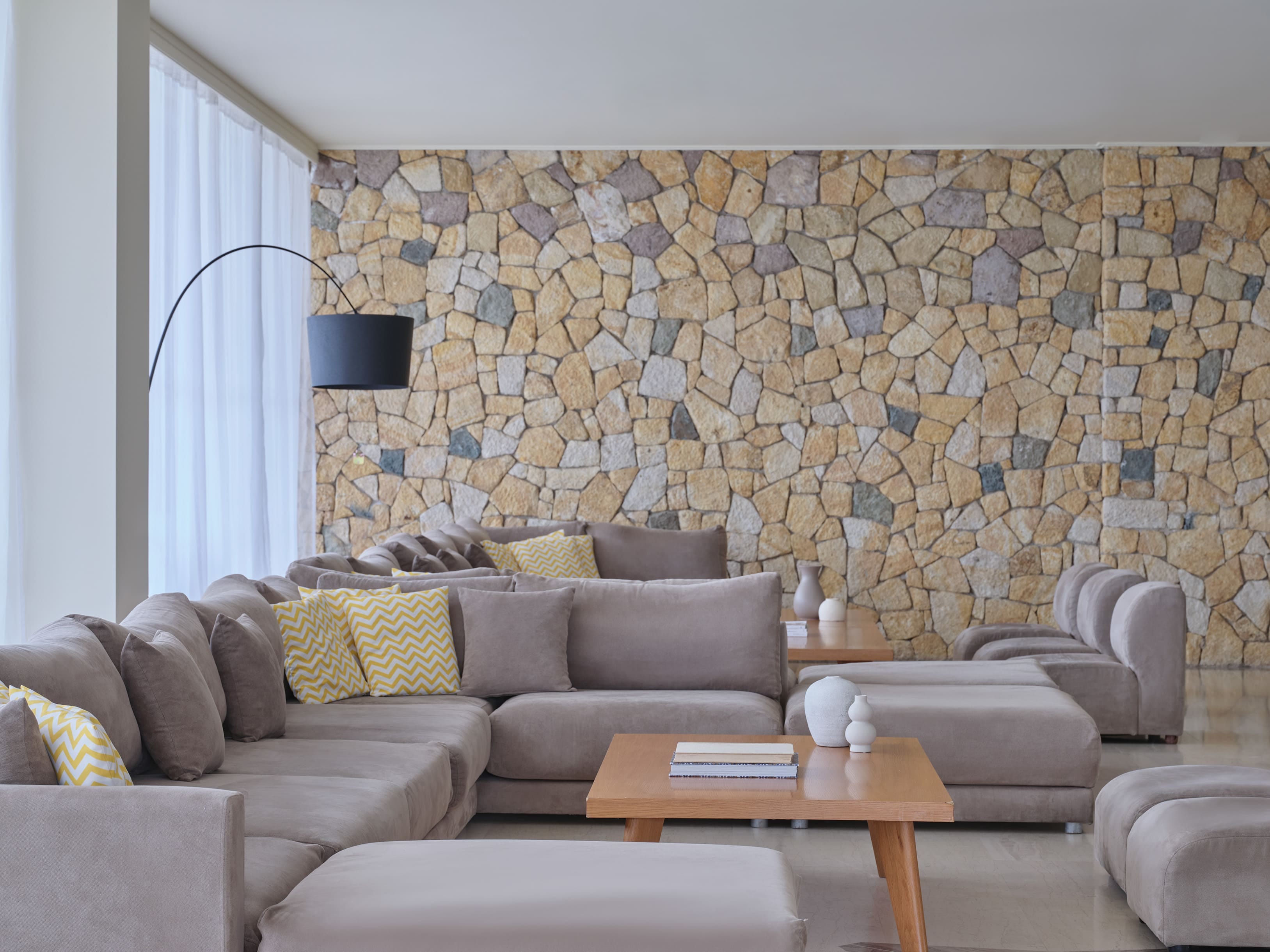 a room with a couch and a table with a wall of rocks