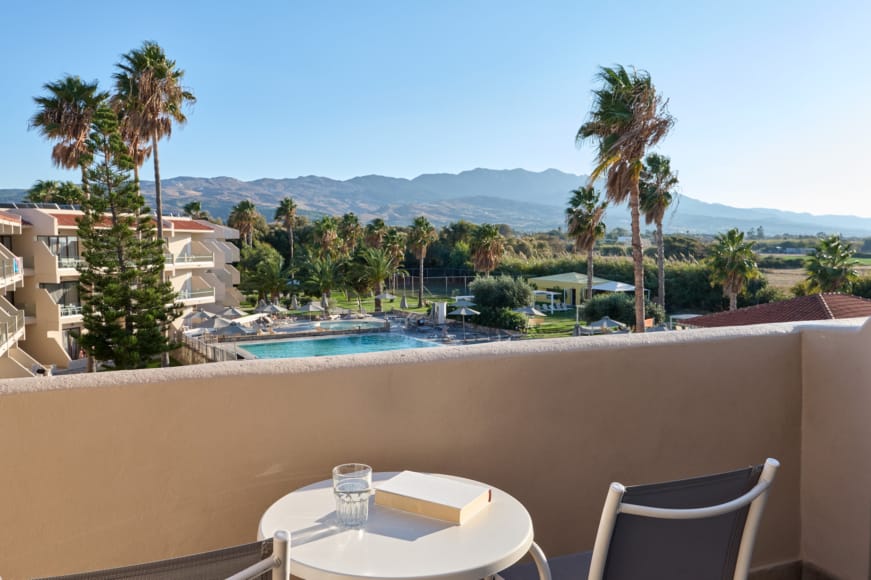 a pool with a deck and chairs by it and palm trees