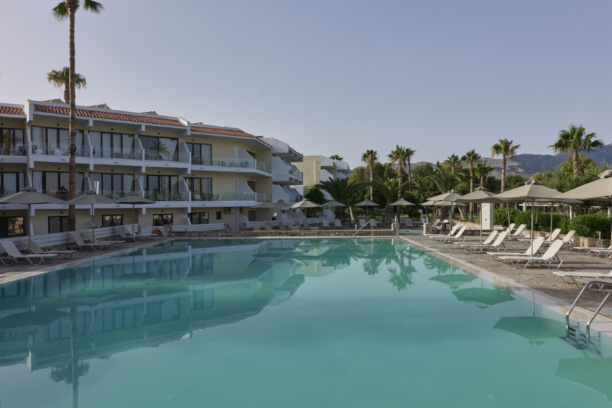 a swimming pool with palm trees and a building in the background