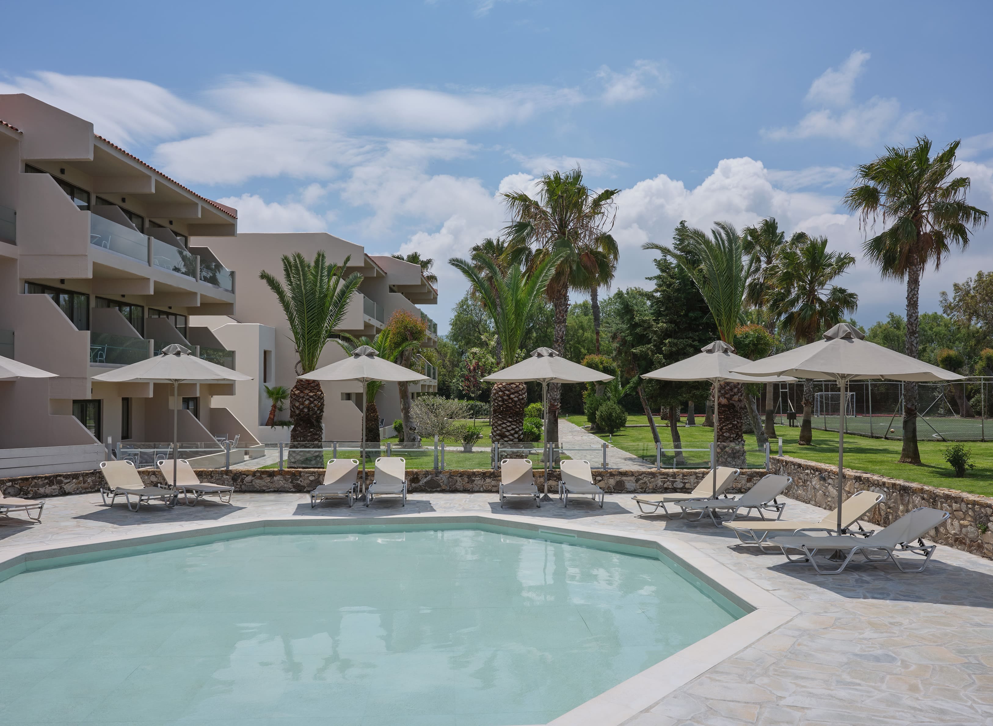 a pool with lounge chairs and umbrellas by a building