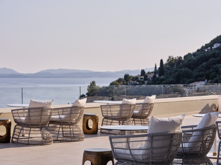 a patio with chairs and tables overlooking a body of water