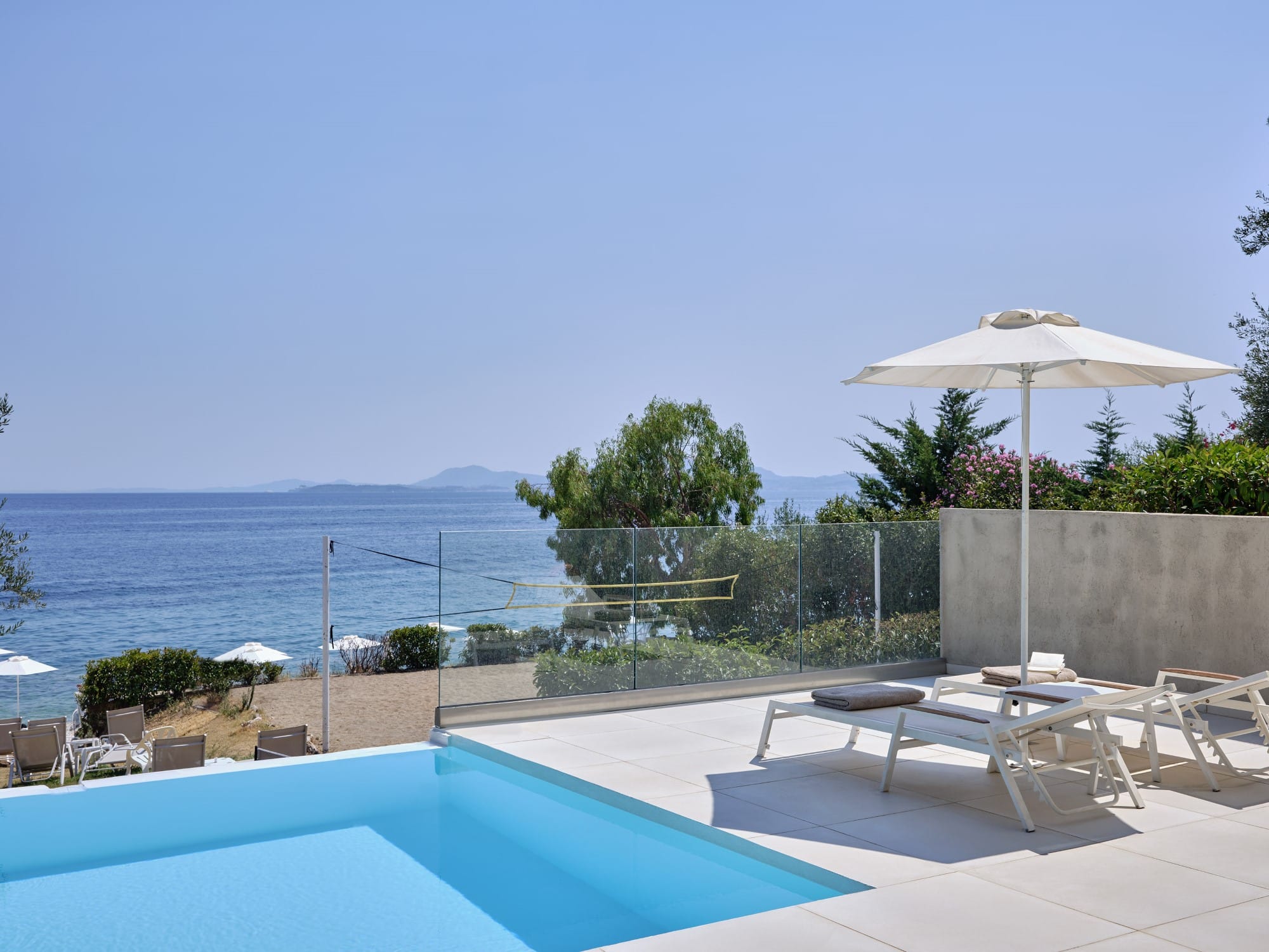 a pool with chairs and umbrellas by a beach
