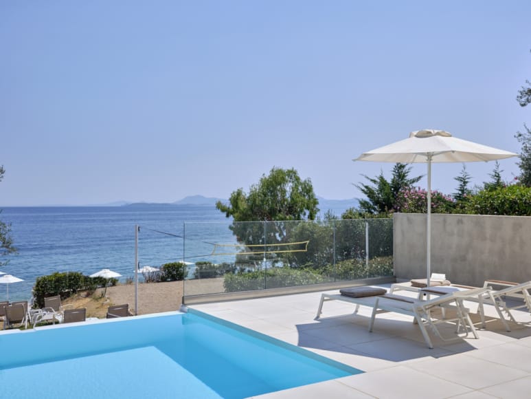 a pool with chairs and umbrellas by a beach