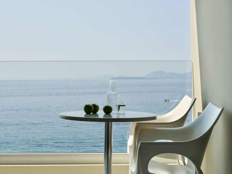 a table and chairs by a window overlooking the ocean