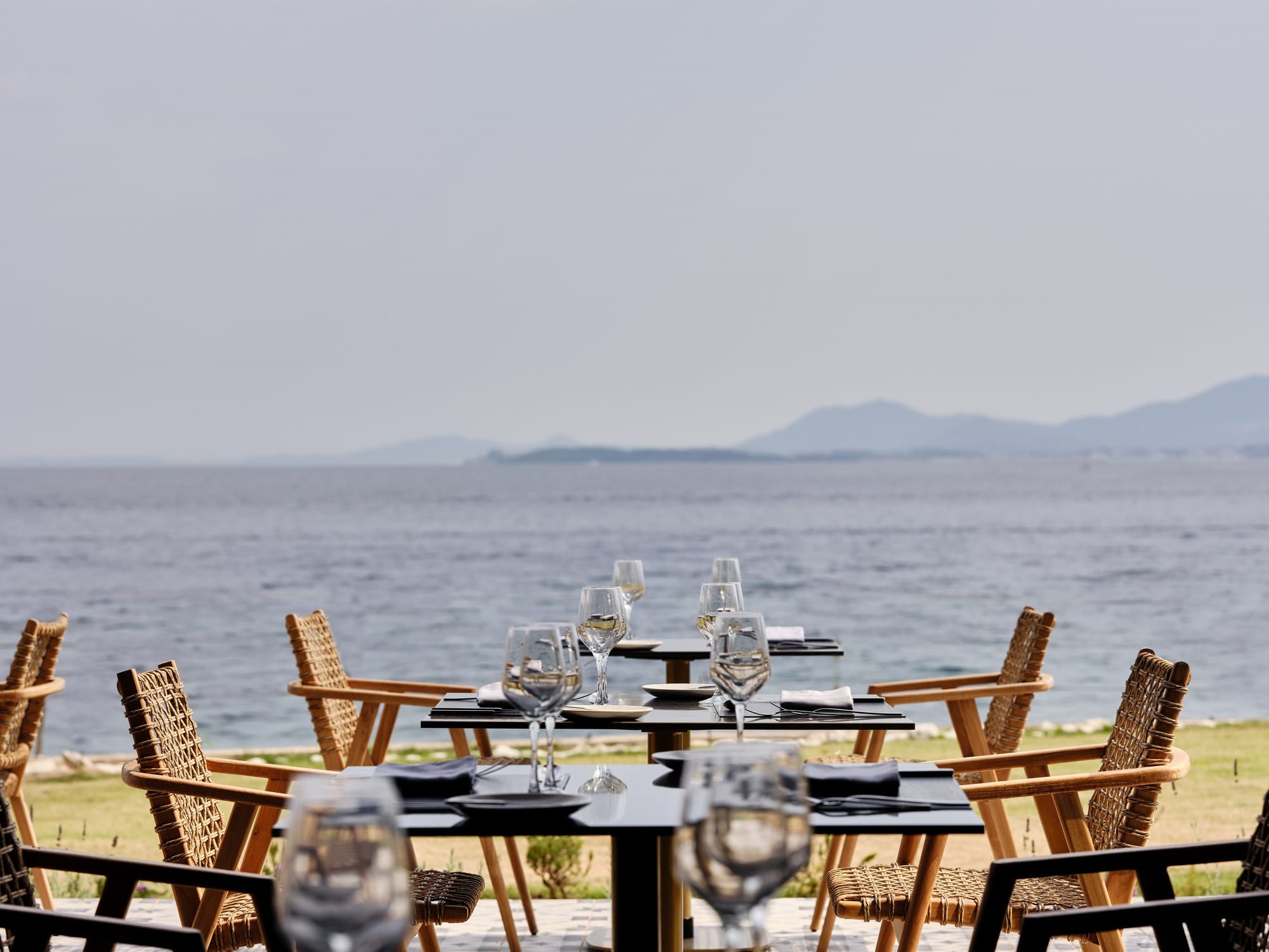 a table with glasses on it by a body of water