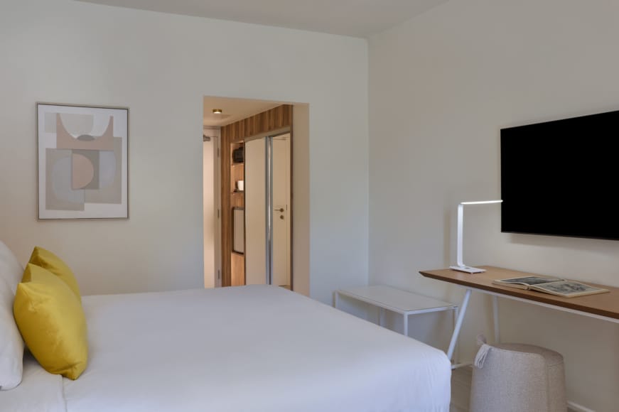 a room with a bed desk and a tv