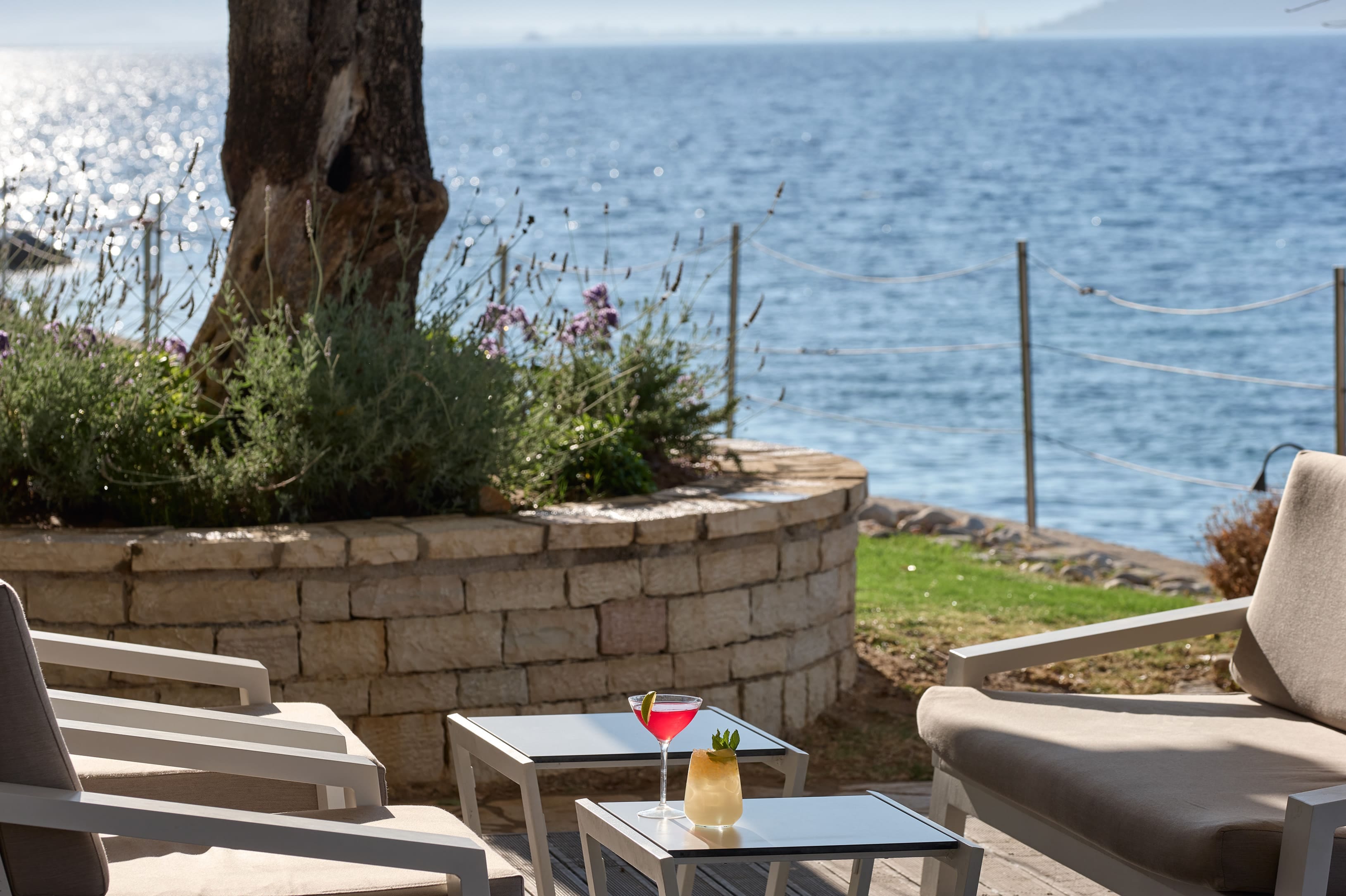 a patio with a table and chairs and a body of water in the background
