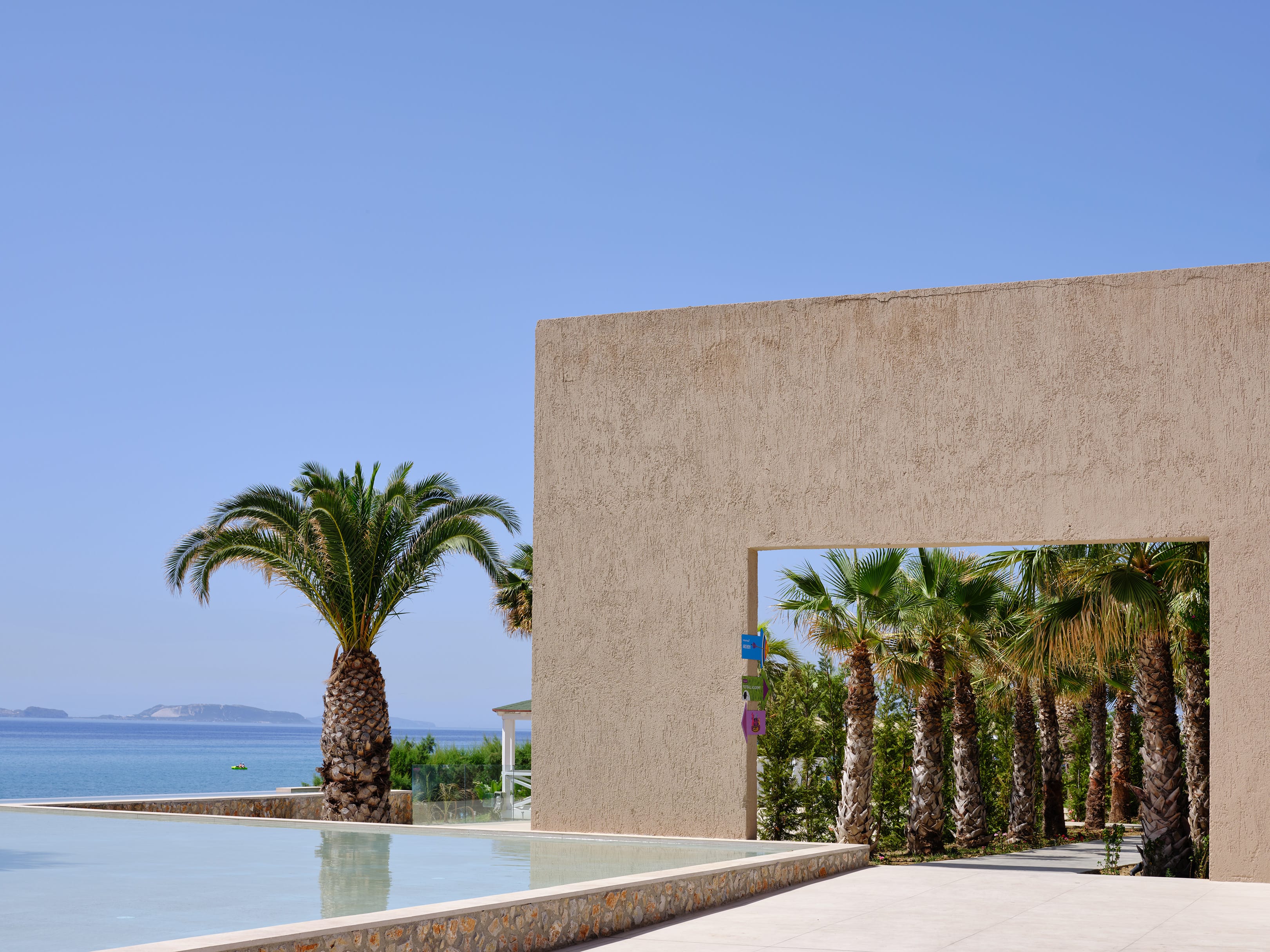 a building with palm trees and a body of water in the background