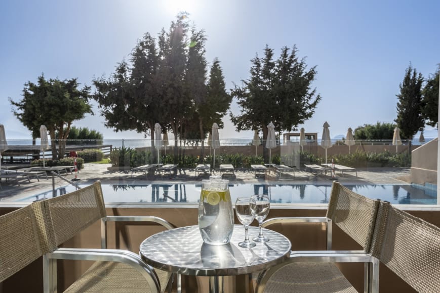 a table with glasses and a glass on it by a pool