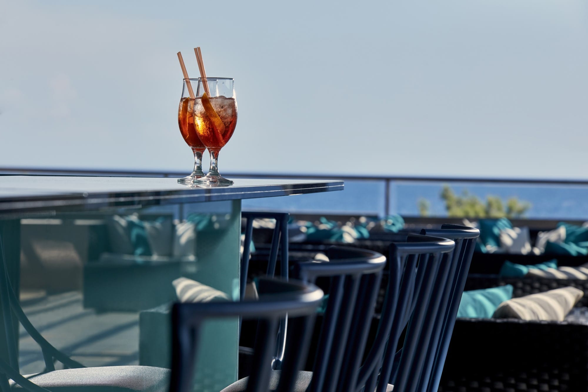 a glass of red liquid on a table with a computer and chairs