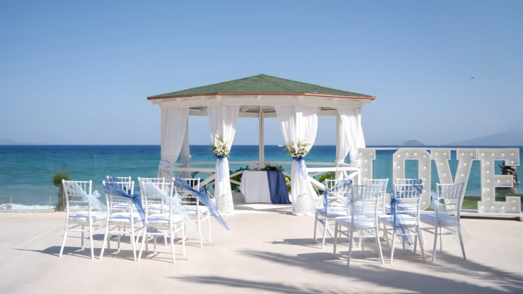 a beach with white chairs and umbrellas