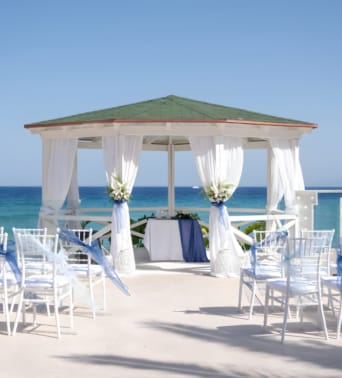 a beach with white chairs and umbrellas