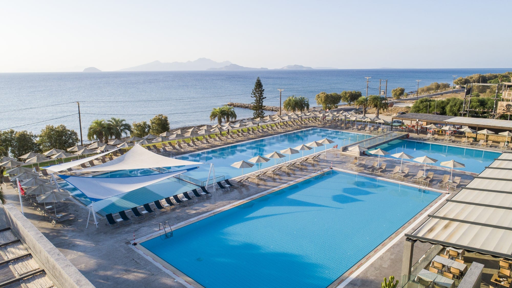 a swimming pool with a beach and trees in the background