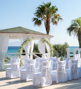a row of white chairs on a beach
