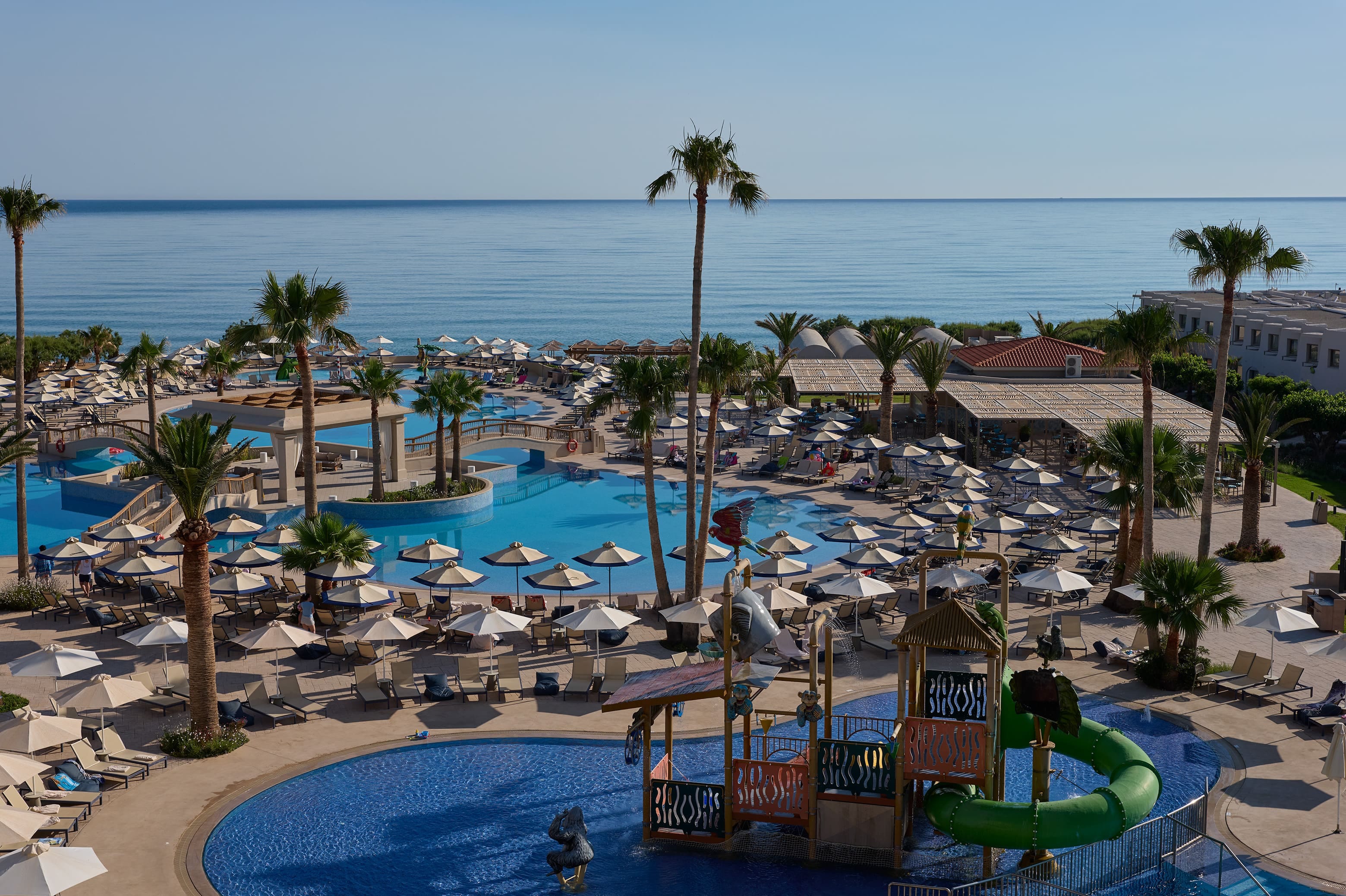 a pool with umbrellas and chairs by a beach