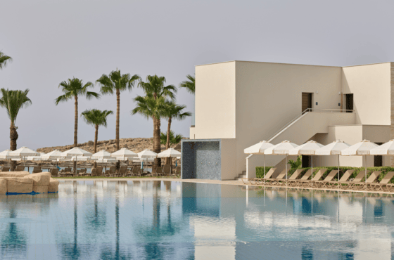 a pool with white buildings and palm trees by it