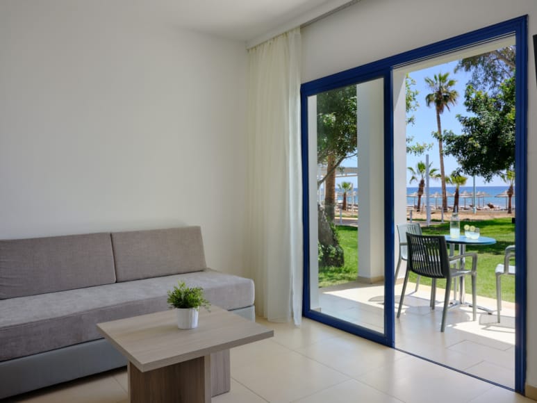 a room with a couch and a table with chairs and a view of the ocean