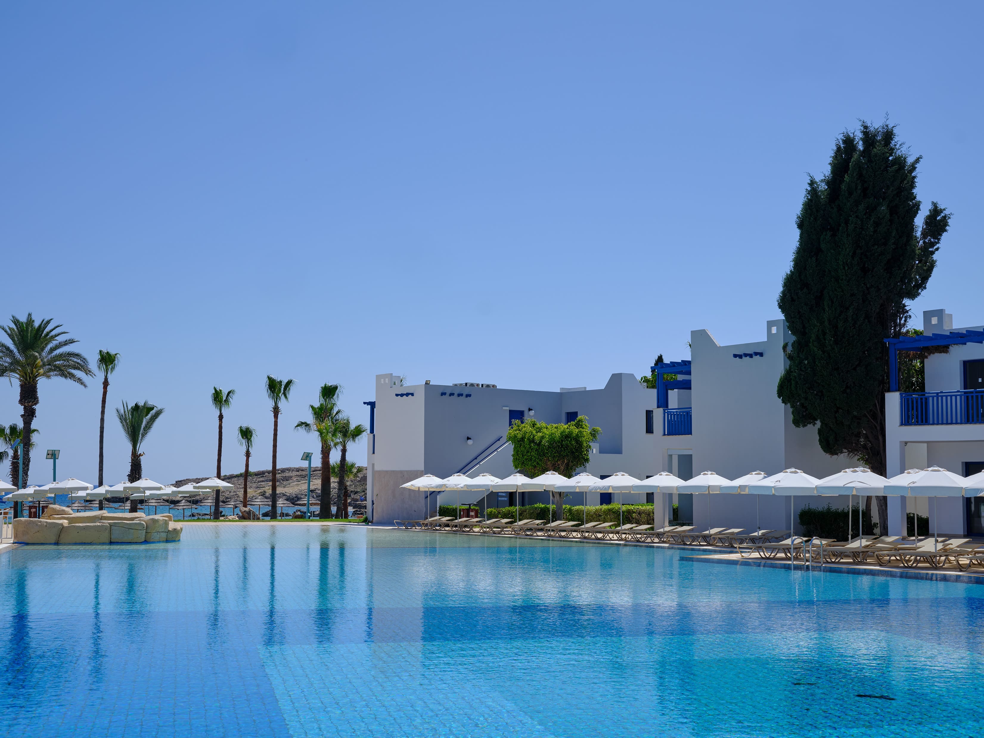 a pool with white buildings and palm trees