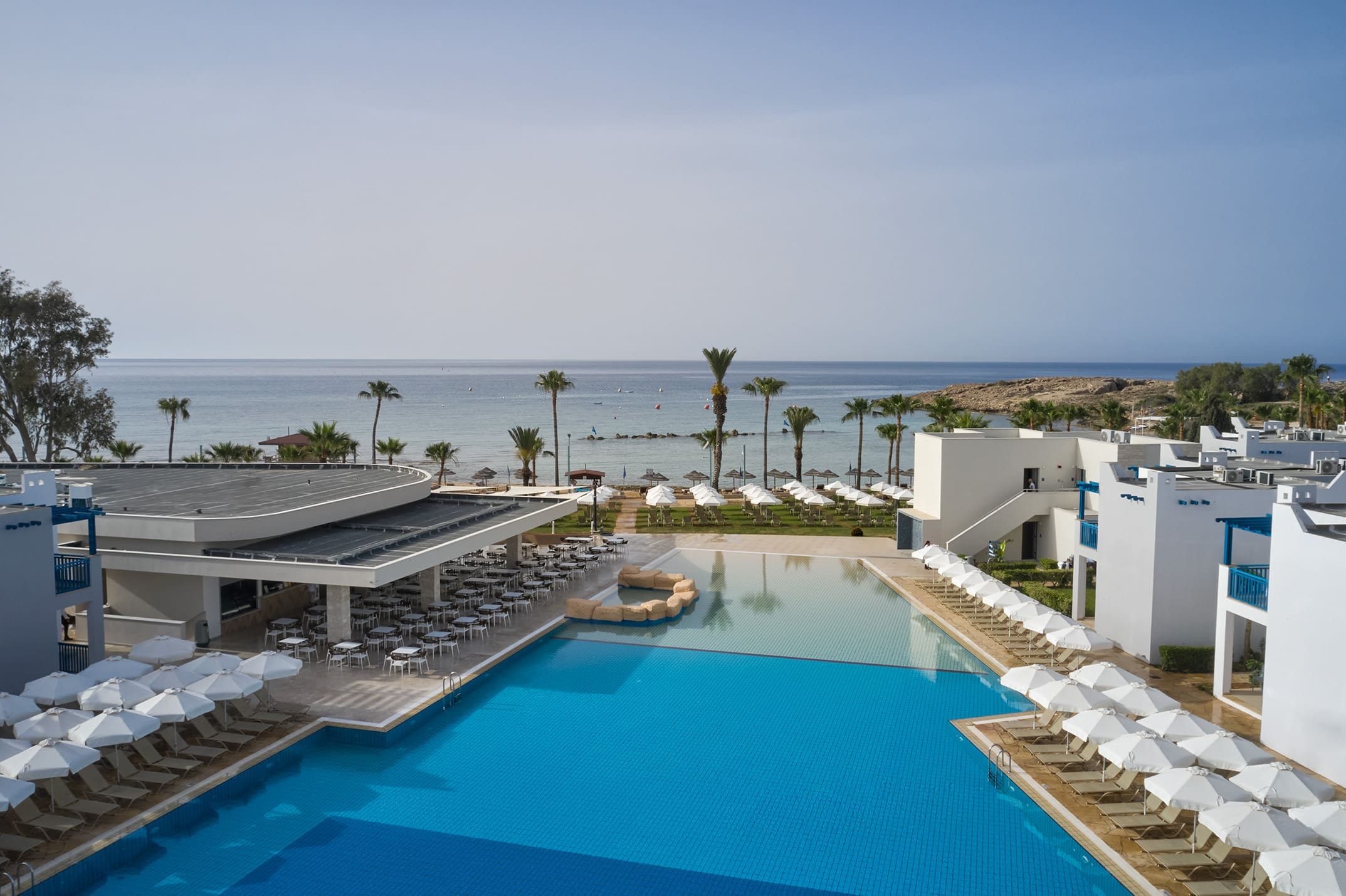 a pool with a deck and chairs by the water